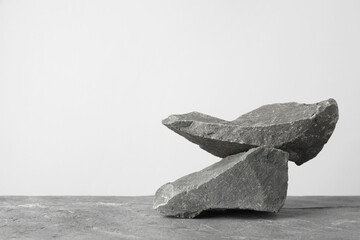 Presentation for product. Podium made of stones on grey table. Space for text