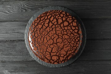 Delicious chocolate truffle cake on black wooden table, top view