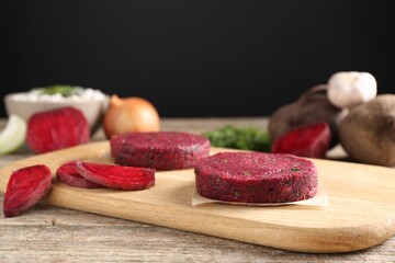 Vegetarian product. Uncooked beetroot cutlets and ingredients on wooden table