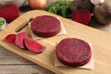 Vegetarian product. Uncooked beetroot cutlets and ingredients on wooden table