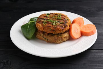 Vegetarian product. Tasty carrot cutlets, vegetable and basil on black wooden table