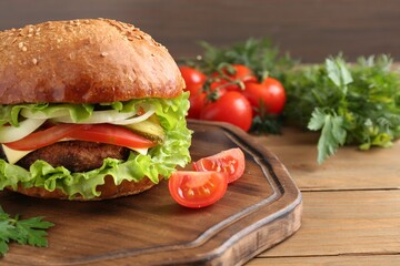 Delicious vegetarian burger served on wooden table, closeup