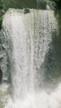 Water cascades under sunlight in slow motion of Hikong Alo Waterfall. Lake Sebu. Mindanao, Philippines. Vertical view.