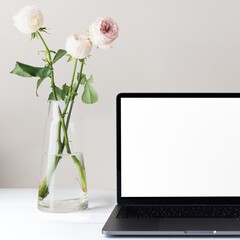 Laptop with blank screen, white roses in vase