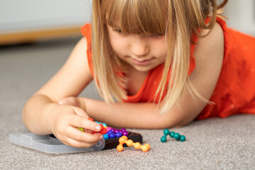 A focused girl is engaged in a colorful logic game. Games for children's development