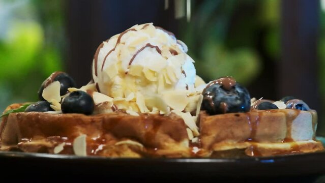 Almond pieces gracefully join pie topped with sculpted ice cream scoop. Professional cook prepares dessert adorned with fresh blueberries