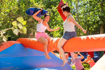 Women holding soft pillows and fighting in adventure park. Family having fun in amusement park.