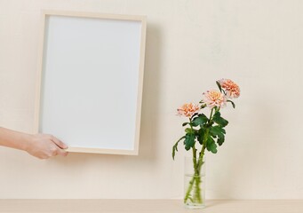 Blank white picture frame, chrysanthemums in transparent vase, minimal feminine home decor