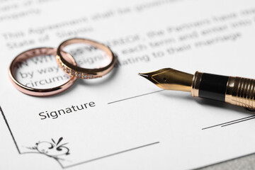 Fototapeta premium Marriage contract, fountain pen and wedding rings on table, closeup