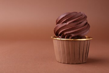 Delicious chocolate cupcake on brown background, closeup. Space for text