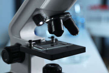 Microscope with glass slide on blurred background, closeup