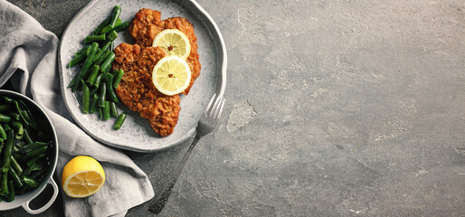 Tasty schnitzels served with lemon and green beans on grey table, flat lay. Banner design with space for text