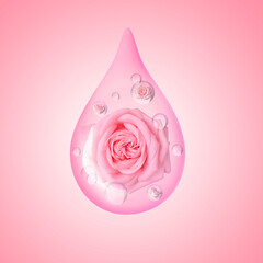 Drop of rose essential oil with flowers on pink background