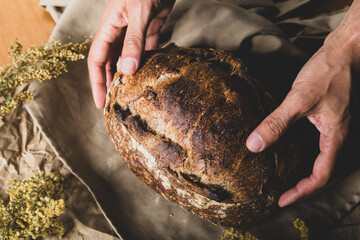 Bread so good that it's worth it. person takes in his hands a loaf of bread made with artisanal...