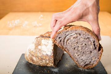 Bread so good that it's worth it. person takes in his hands a loaf of bread made with artisanal...