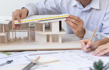 Professional male engineer hand measure house model by using ruler while beautiful cooperative...