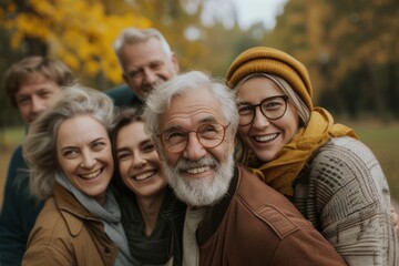 Portrait of a happy senior couple with their family in autumn park