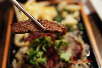젓가락으로 집은 스테이크 고기