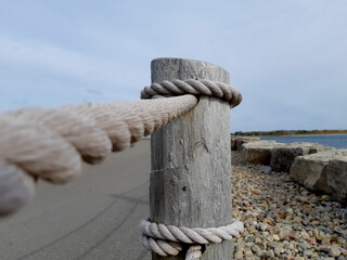 closeup of a wooden post with heavy rope to act as a waterside roadway guard rai