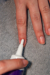 vertical photo of hands using cuticle remover