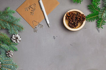 Fir branches, pine cones and envelope on grey stone surface, Christmas background