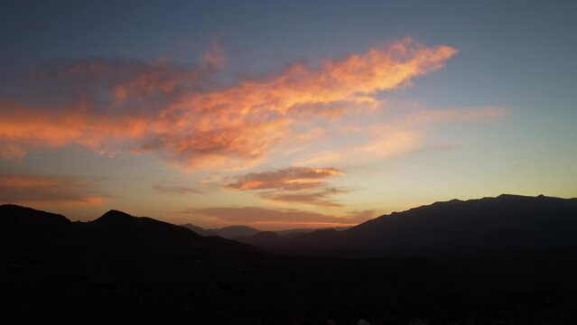 Fiery sunrise silhouetting Pestera Village mountains, with vibrant orange clouds