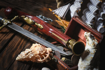 Pirate concept background front view. Treasure chest, sword and musket gun on the table close up....