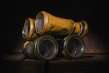  Retro binoculars on the old wooden desk table background front view close up. Travel background.