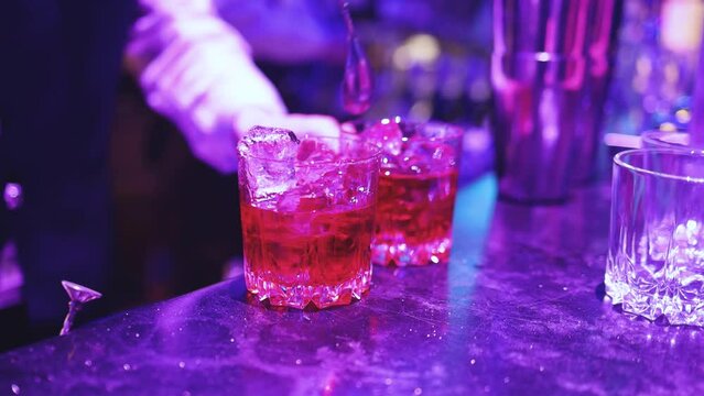 Bartender working, beautiful row line of different coloured liquor alcohol cocktails on a party in a bar, and others on catering banquet on event, barman mixing drinks and beverages in a club
