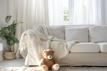 Scandinavian hygge interior design of modern white living room, white sofa with teddy bear home. Clear light through window.