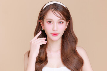 Pretty Asian beauty woman curly long hair with Korean makeup glowing face and healthy facial skin portrait smile on isolated beige background. Cosmetology ,Plastic surgery.