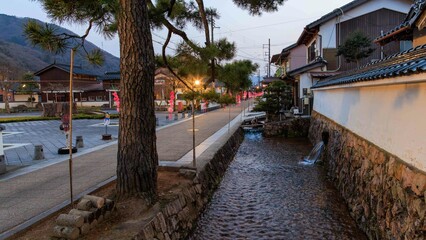 Flowing water in canal by historic street in Takeda Town, Japan at dusk