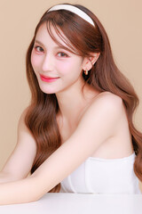 Obraz na płótnie Canvas Pretty Asian beauty woman curly long hair with Korean makeup glowing face and healthy facial skin portrait smile on isolated beige background. Cosmetology ,Plastic surgery.