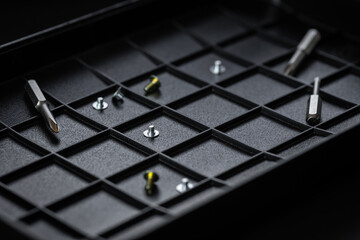 Torx drive bit and aluminum bit driver on black sorting tray. Screws and drive bits. Screwdriver handle with magnetic bit socket and knurled grip.