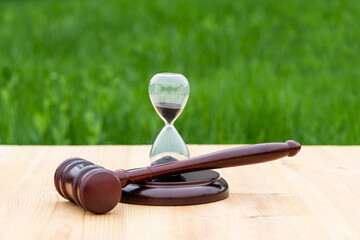 Judge's gavel and hourglass on grass background