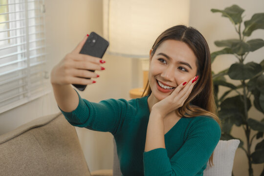 A beautiful Asian woman spends her free time on her sofa at home taking selfie photos, The weekend was spent relaxing at home in a happy and cozy home with a beautiful Asian woman.