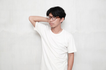 Young man wearing white t-shirt and glasses on white background smiling looking to the side and...