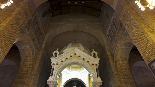 Solemn interior of the Catedral Metropolitana, Medellin, with its iconic crucifix and arched brickwork, embodying serene spirituality. Colombia
