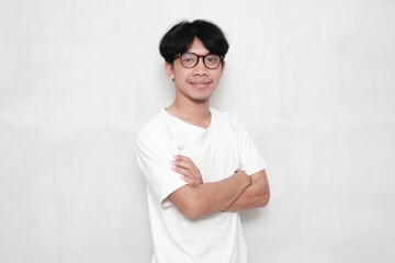 Young Asian man wearing t-shirt and glasses on white background smiling