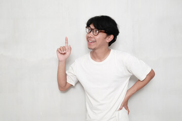 Asian man wearing glasses happy smile point finger at copy space white background