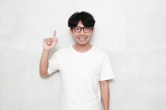 Young Asian man pointing finger up with smiling face