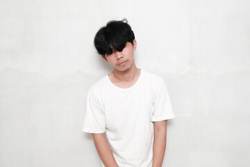 Young Asian man wearing a white t-shirt showing a frustrated gesture against a white background