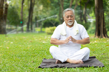 asian senior man meditating and doing yoga in the park