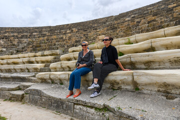 Salamis, Cyprus - April 16, 2024 2 women sitting in an amphitheater in an ancient ruined city,...