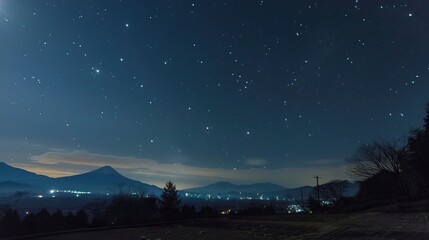 Fototapeta premium Starry night over a serene landscape with mountains and city lights