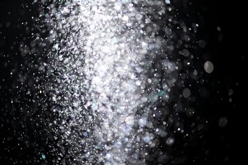 Obraz premium White falling glitter sequin confetti on dark black background