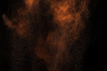 Brown grunge texture. Orange powder explosion on black background. Flame cloud. Yellow dust...
