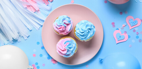 Plate with delicious cupcakes and decorations on blue background. Gender reveal party concept