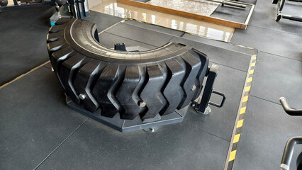 A tire flip machine sits on a gym floor, offering a robust tool for strength training and functional fitness workouts.