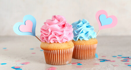 Delicious cupcakes with pink and blue frosting on table against white grunge background. Gender reveal party concept